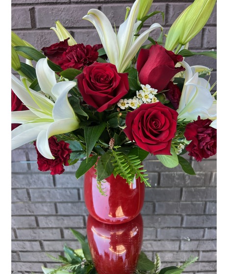 Red roses and white lilies in a red glass vase.